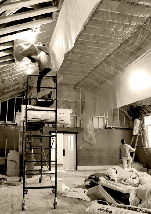 Two people doing wall insulation installation in a building